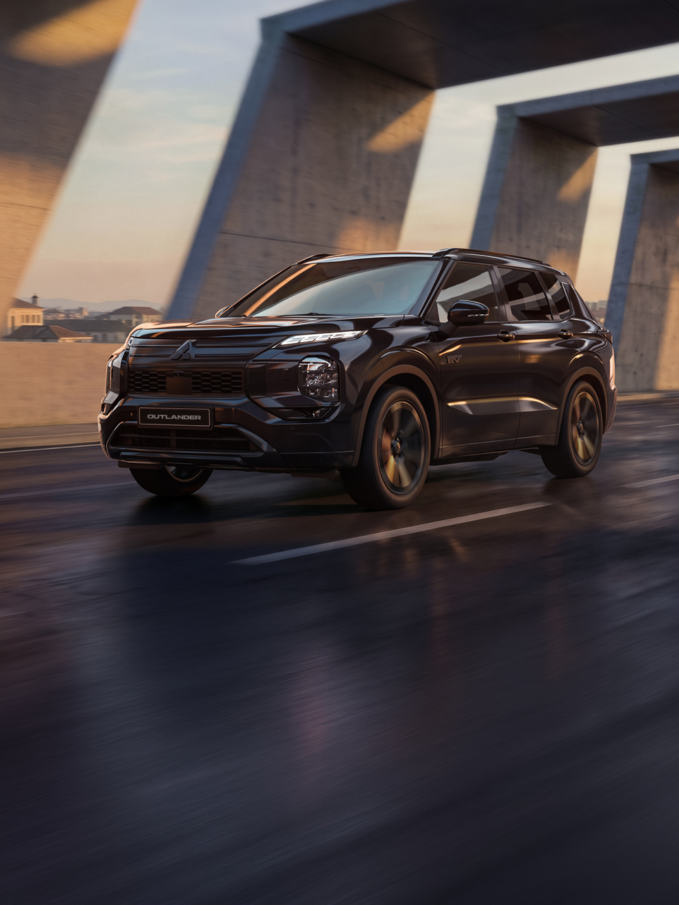 Schwarzer Mitsubishi Outlander Black in dynamischer Frontansicht unter einer modernen Betonbrücke bei Sonnenuntergang